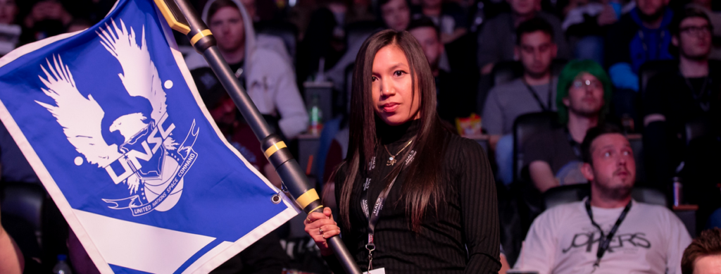 Photo of fan at an HCS event holding a blue cosplay flag from CTF in Halo 5.