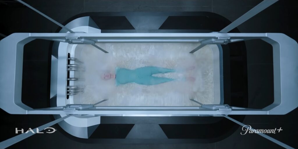 Trailer shot of a figure being lowered into an acidic tub.
