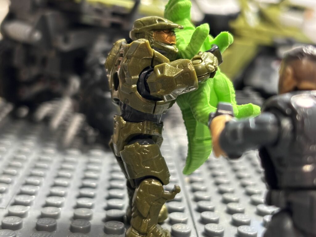 Toy photography of the Master Chief running off with a toy dinosaur.