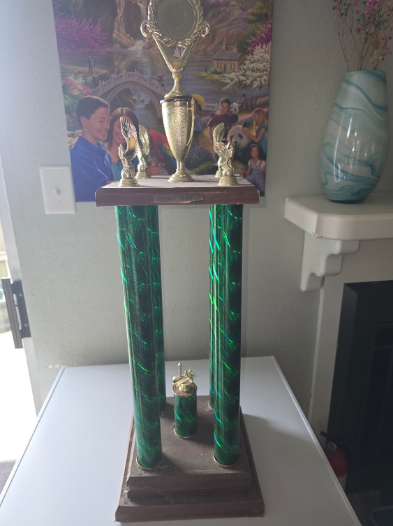 A large trophy made of 4 green pillars topped by a gold cup.